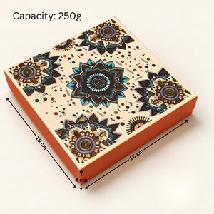 A square decorative gift box with a cream top featuring a colorful mandala pattern and orange sides, shown with dimension arrows and text reading 'Capacity: 250g' and measurements 16 cm by 16 cm by 4 cm on a light background.