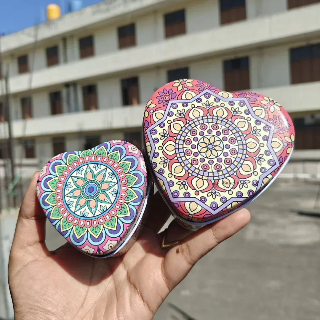 Colorful mandala print heart tin boxes for gift packaging by Bakeyy.com, held outdoors.