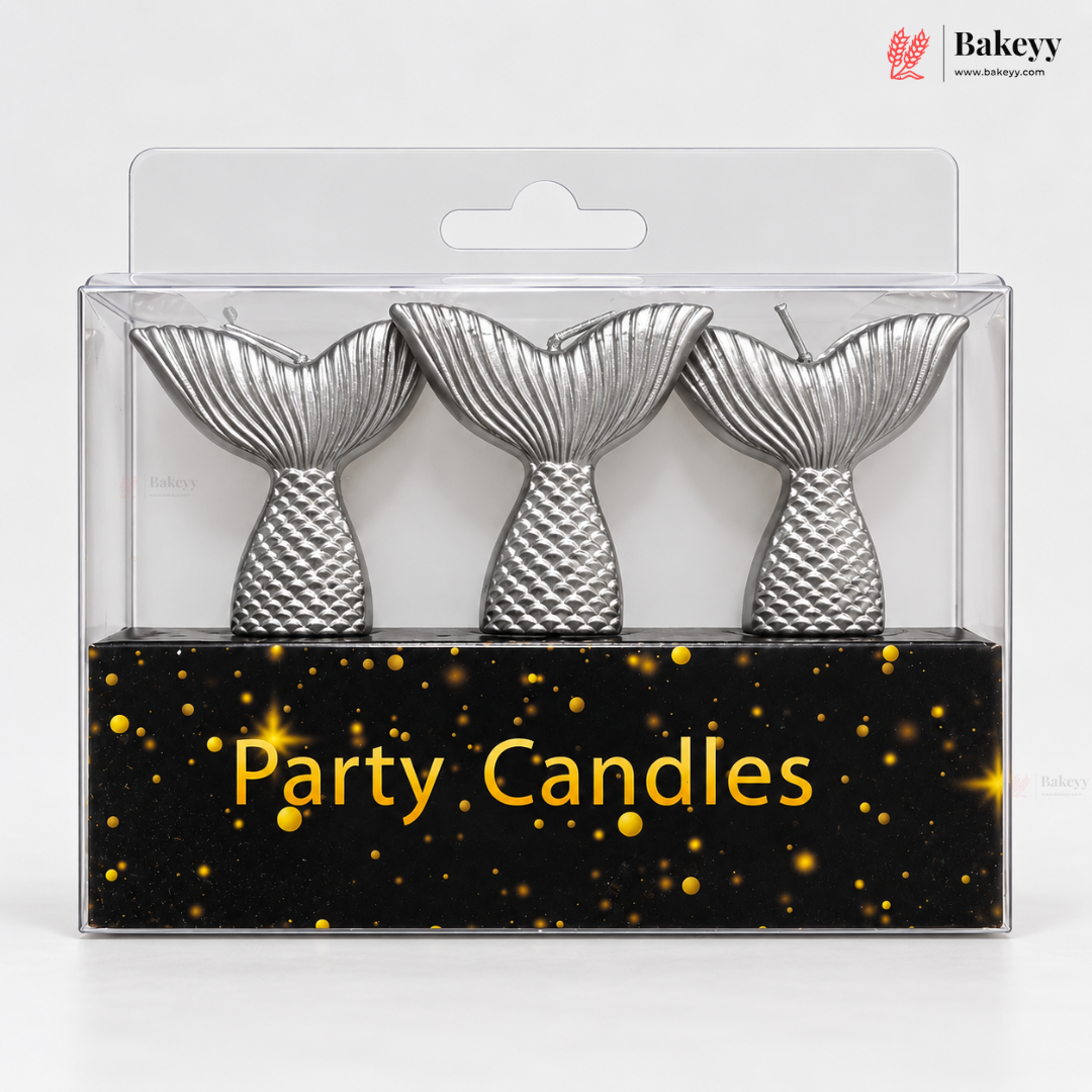 Three silver mermaid tail party candles in a clear blister pack with a black base printed with gold text reading 'Party Candles' and gold speckles. A Bakeyy logo appears in the top right corner.