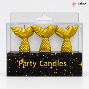 Three gold mermaid tail party candles in a clear plastic blister pack with a black backing card labeled 'Party Candles' and a Bakeyy logo in the top right.