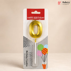 A gold metallic letter 'O' birthday candle in its retail blister packaging, featuring a red 'HAPPY BIRTHDAY' header and balloon graphics on a beige background.