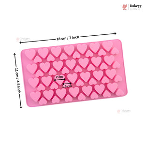 Pink rectangular silicone mold with heart-shaped cavities, shown with black dimension arrows and text indicating 18 cm by 11 cm (7 x 4.3 inches), on a white background with Bakeyy branding.