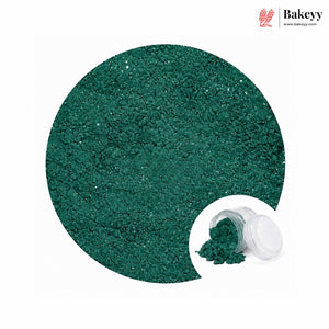 A circular close-up of sparkling dark green glitter powder, with a small inset showing the powder spilled from a clear jar with a white lid. The Bakeyy logo appears in the top right on a white background.
