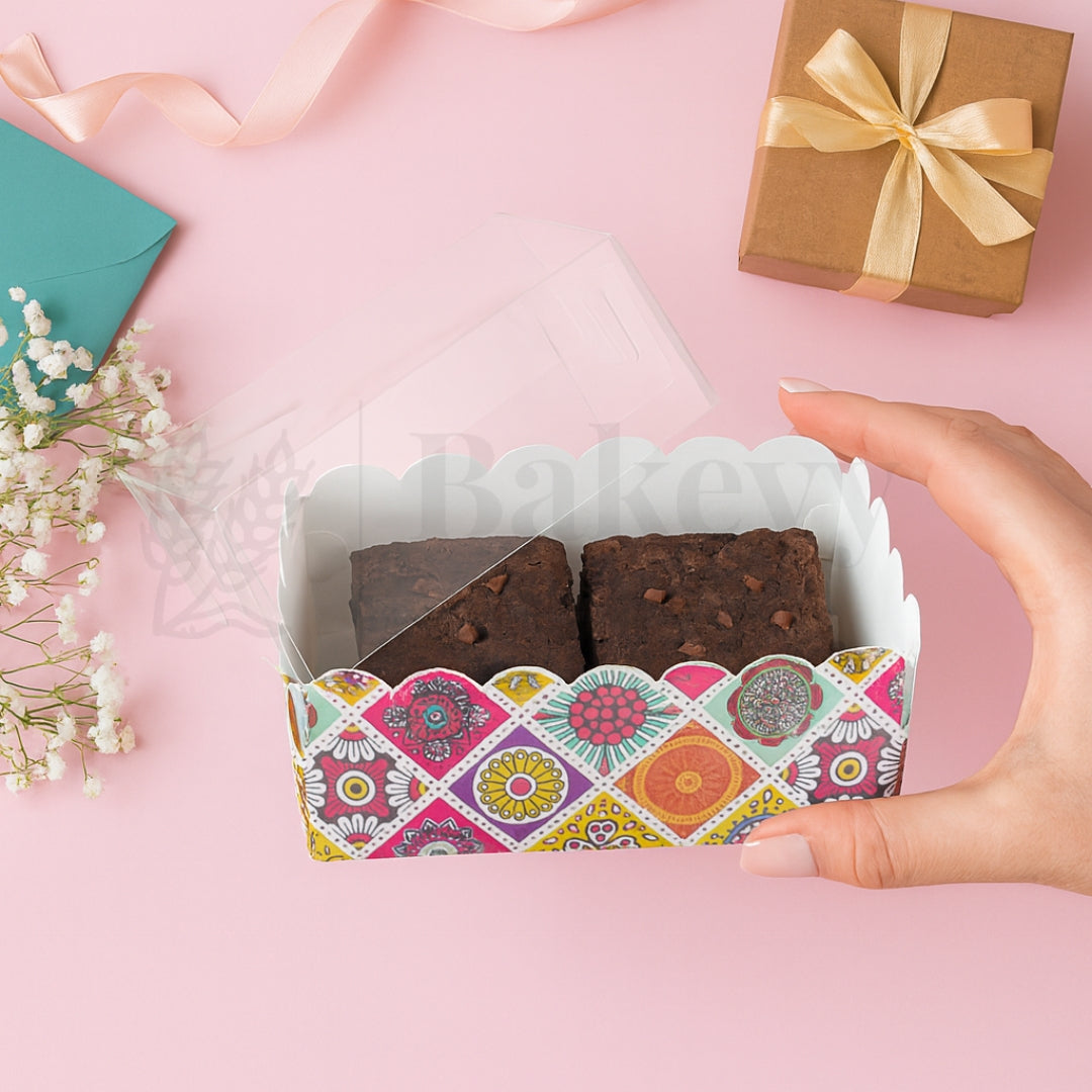 Hand holding a box of brownies with a decorative pattern on a pink background