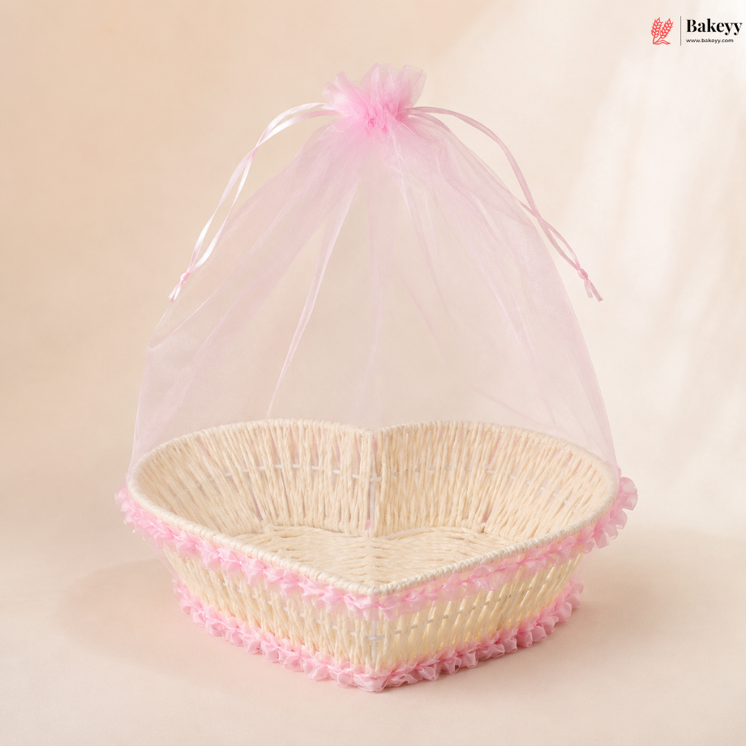 Heart-shaped wicker basket with pink decorative trim and sheer cover on a beige background, featuring the Bakeyy brand.