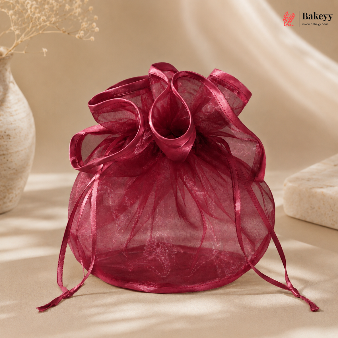 Pink organza drawstring bag on a beige surface with a soft focus background