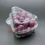 Clear plastic container with red grapes on a gray background