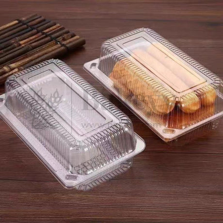 Clear plastic food containers with baked goods on a wooden surface