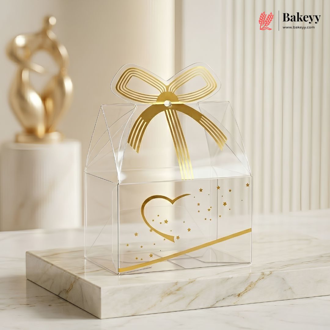 Clear gift box with gold bow and heart design on a marble surface, featuring the Bakey brand.