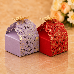 Two decorative gift boxes, one purple and one red, with floral designs on a marble surface.