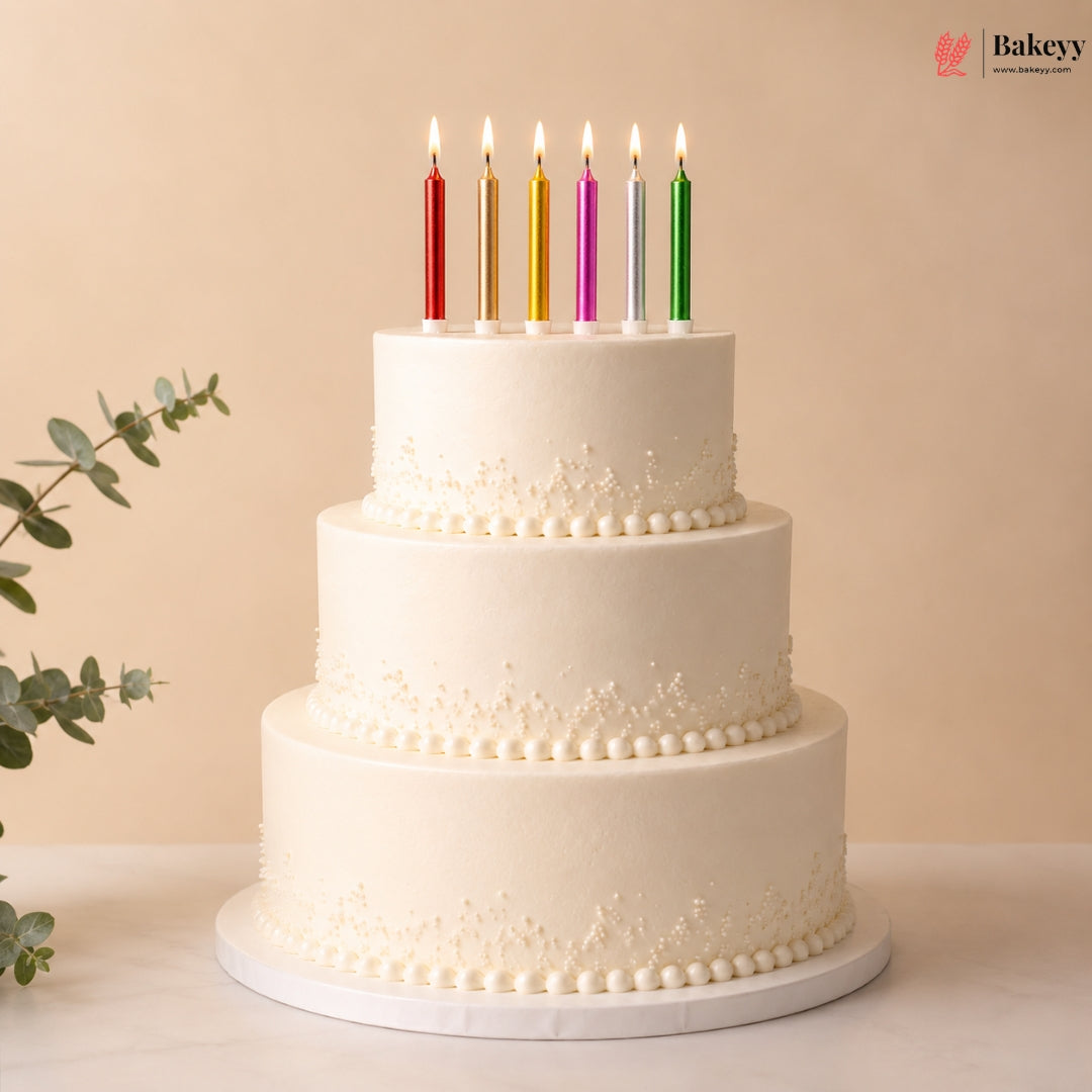 Three-tiered white cake with colorful candles on a beige background