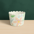 Floral design cupcake wrapper on a wooden surface with a green background