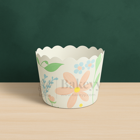 Floral design cupcake wrapper on a wooden surface with a green background