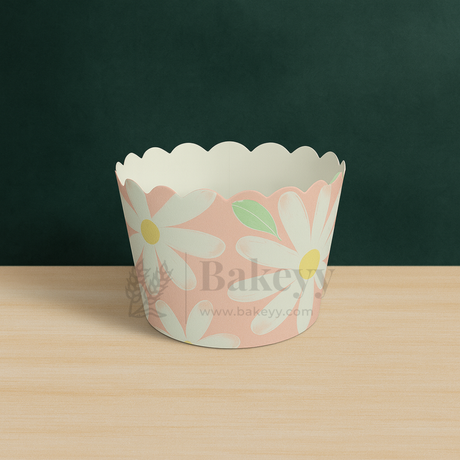 Floral paper cupcake wrapper on a wooden surface with a dark green background