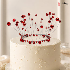 White cake with a red decorative crown on top, featuring the Bakeyy brand.