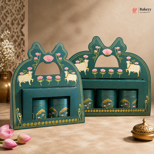 Two decorative teal gift boxes with floral and animal illustrations, each holding three matching teal cylindrical tins, displayed on a beige surface with floral props and a warm neutral background.