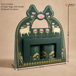 A dark green decorative gift box with gold detailing, pink lotus flowers, and cow illustrations, shown with dimension markers indicating 26 cm height, 23 cm width, and 8 cm depth. Two matching green cylindrical tins are placed inside a front slot.