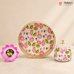 A decorative ceramic lotus-themed serving set on a warm beige background, featuring a round plate with a gold-toned rim, a matching lidded jar, and a pink lotus flower bowl. The white ceramic is decorated with pink lotus flowers and green leaves, and the pink flower bowl has a gold-toned center.