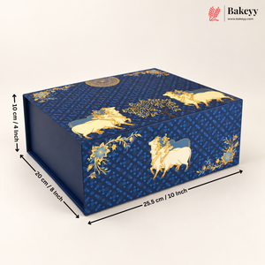 A rectangular blue bakery box with gold decorative motifs and dimension arrows showing measurements of 10 cm by 20 cm by 25.5 cm, on a light beige background.