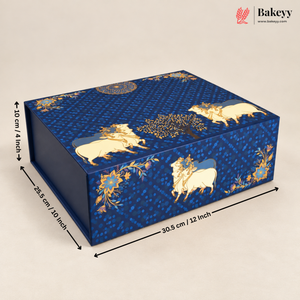 A rectangular blue decorative box with gold and cream cow motifs and floral patterns, shown on a light beige background with dimension arrows and text indicating 30.9 cm length, 28.