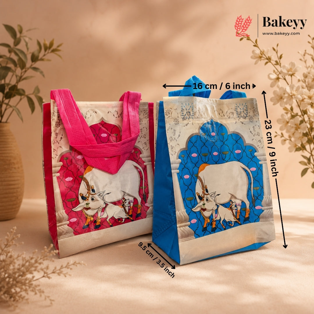 Two decorative reusable gift bags with printed cow illustrations and measurement arrows overlaid, showing dimensions 16 cm by 23 cm and 9.5 cm, on a warm beige background with floral props.