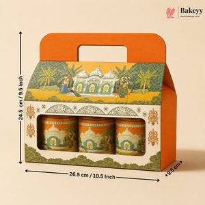 A boxed set of three decorative cylindrical containers with a hinged orange handle lid, shown on a beige background with printed dimensions around it. The packaging features an illustrated architectural scene with green, yellow, and orange tones.