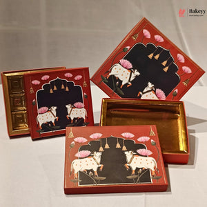A set of decorative gift boxes with red outer panels, black central arches, pink lotus flowers, and two white cows with pink ornaments. One box is open to show a gold interior, and another is shown closed from the front.