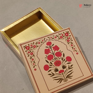 An open rectangular bakery box with a gold interior and a cream-colored lid decorated with a red and green floral illustration, set against a neutral gray background.