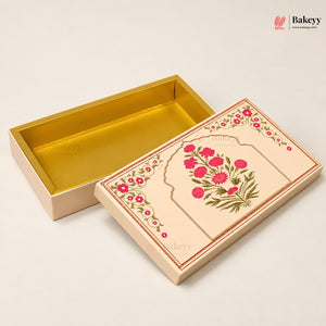 A rectangular bakery gift box with a cream-colored exterior decorated with pink floral patterns and green leaves, shown alongside its open gold-lined interior on a light beige background.