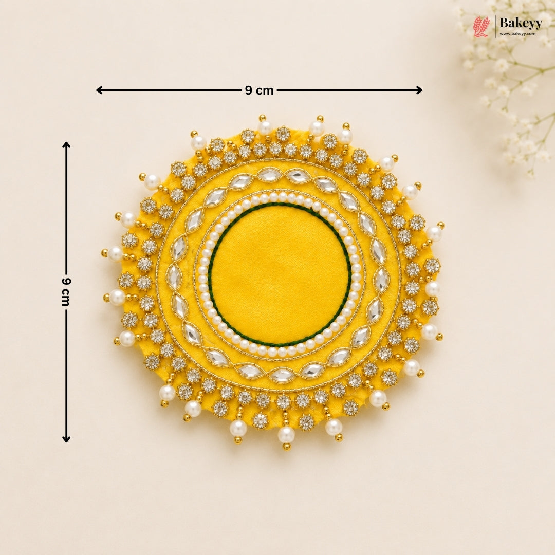 Decorative yellow circular piece with pearl and gemstone details, shown with measurements on a beige background.
