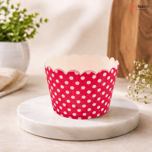 Pink cupcake liner with white polka dots on a marble surface with a blurred background