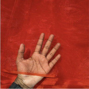 A hand laid flat against a bright red sheer mesh fabric background, showing the texture and transparency of the material.