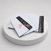 White mailing bag with black strip and red logo on a white platform