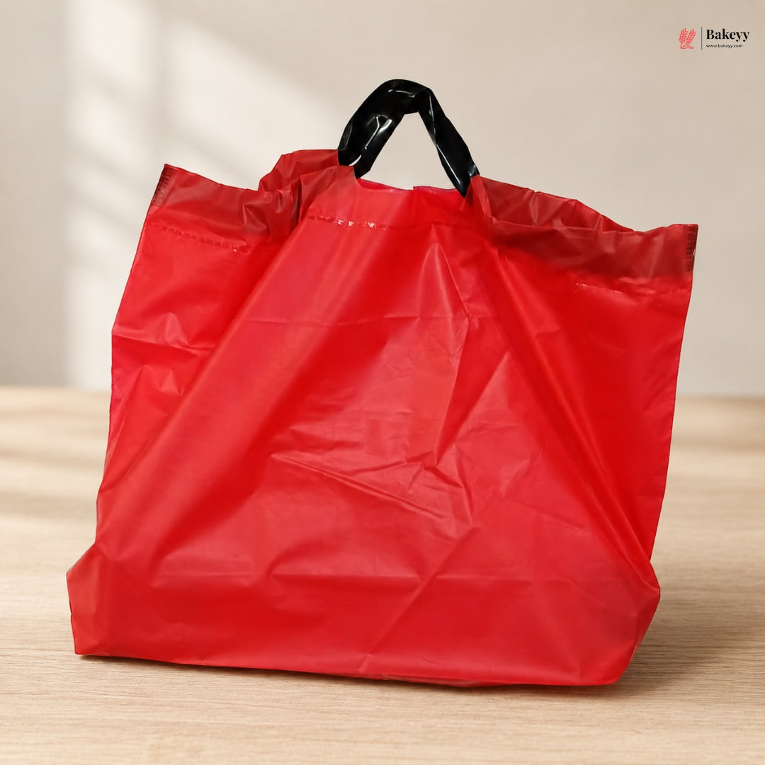 Red plastic bag with a black handle on a wooden surface