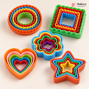 A set of colorful nested cookie cutters in multiple shapes including circles, squares, hearts, flowers, and stars, arranged on a light beige background with a Bakeyy logo in the top right corner.