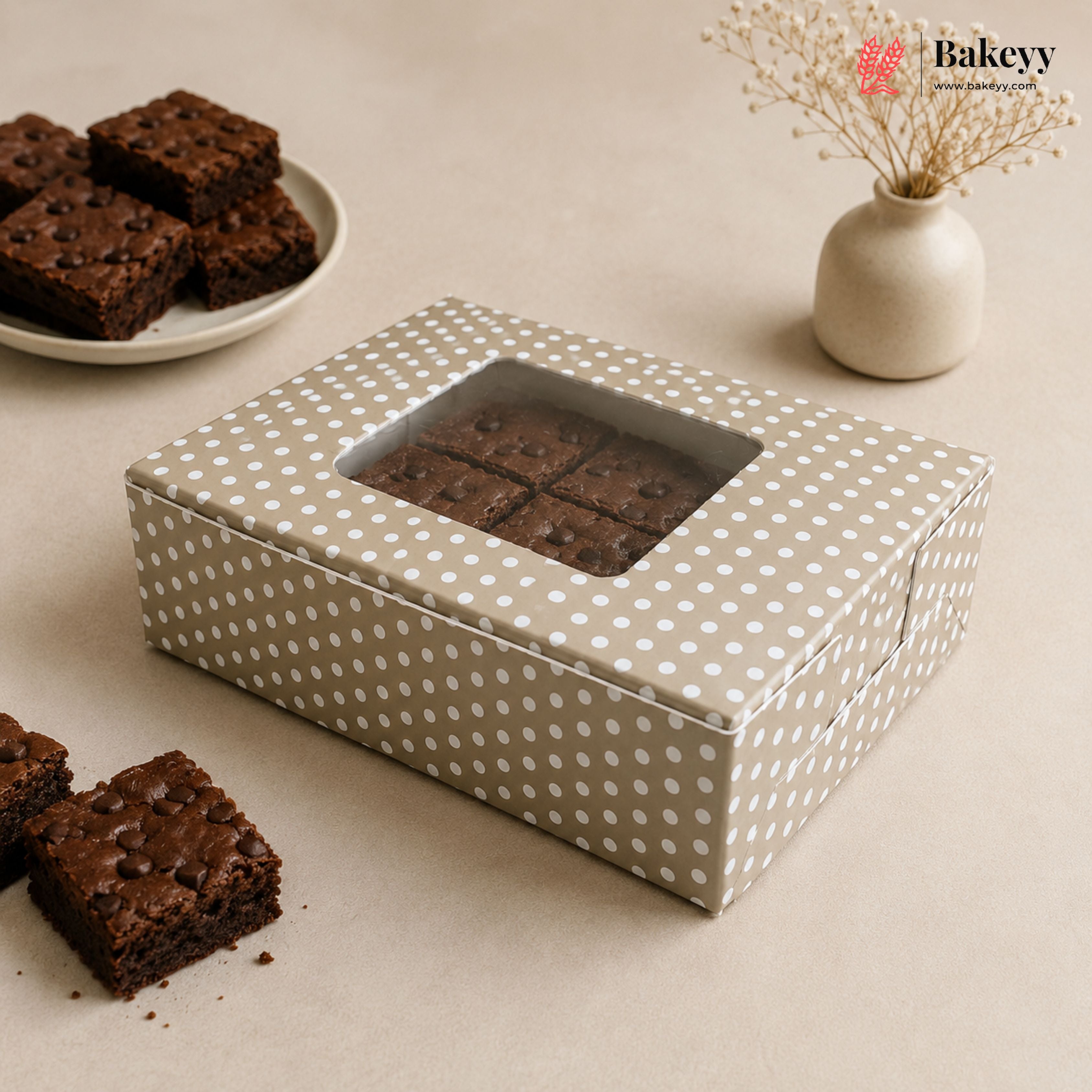 Polka dot brownie box with brownies on a beige surface, featuring the Bakey brand.