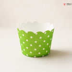 Green cupcake liner with white polka dots on a beige background