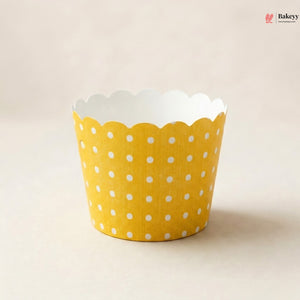 Yellow cupcake liner with white polka dots on a beige background