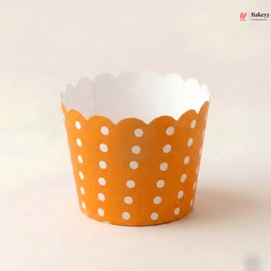 Orange cupcake liner with white polka dots on a light beige background