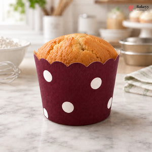 Muffin in a red muffin liner with white polka dots on a marble countertop.