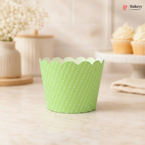 Green polka dot cupcake liner on a light wooden surface with a blurred background