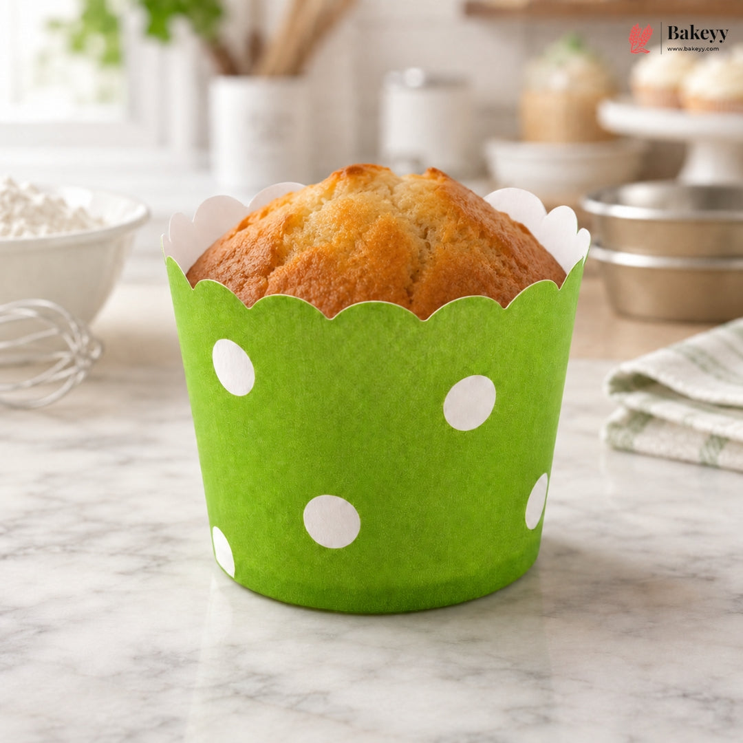 Muffin in a green cupcake liner with white polka dots on a marble surface.