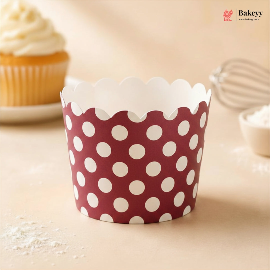 Red and white polka dot cupcake wrapper on a light background with a cupcake and baking tools.