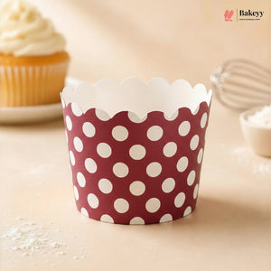 Red and white polka dot cupcake wrapper on a light background with a cupcake and baking tools.