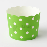 Green cupcake wrapper with white polka dots on a white background