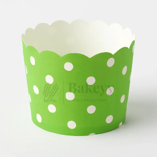 Green cupcake wrapper with white polka dots on a white background