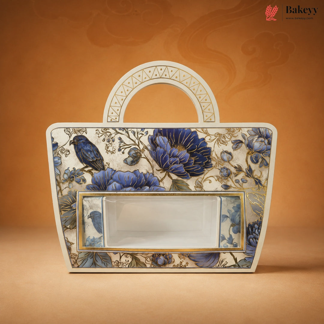 A decorative rectangular cake or pastry gift box with a handle, featuring a blue floral and bird pattern on an ivory background, set against a warm orange-brown backdrop. The Bakeey brand logo is visible in the top right corner.