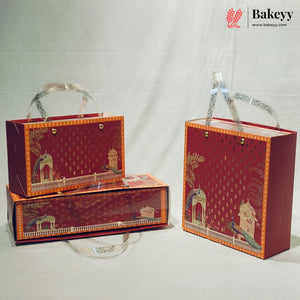Three red and gold decorative gift boxes with illustrated architectural designs and silver patterned handles, arranged on a white studio background. A Bakeyy logo watermark appears in the top right corner.