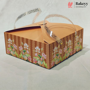 A square cardboard bakery box with a brown striped and floral patterned exterior, clear plastic handles, and a Bakeyy logo watermark in the top right corner.