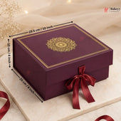 A rectangular purple gift box with a gold mandala design on the lid, tied with a dark red ribbon, shown on a marble surface with dimension arrows and labels indicating 25.5 cm by 10 cm by 20 cm.